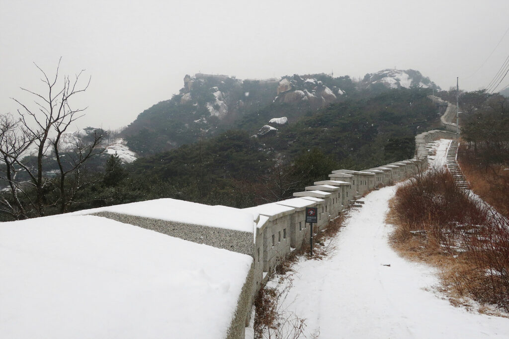 인왕산 올라가는 길에 위쪽을 바라본 풍경. 성벽과 등산로, 인왕산 바위 곳곳에 눈이 덮여 있다.