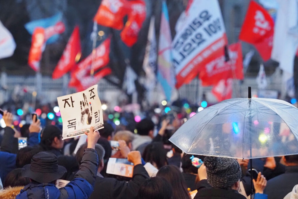 "자주독립"이라고 적힌 손팻말을 든 시민, 우산을 펼친 시민을 비롯해 수많은 시민들이 광장에 나와 있는 모습.