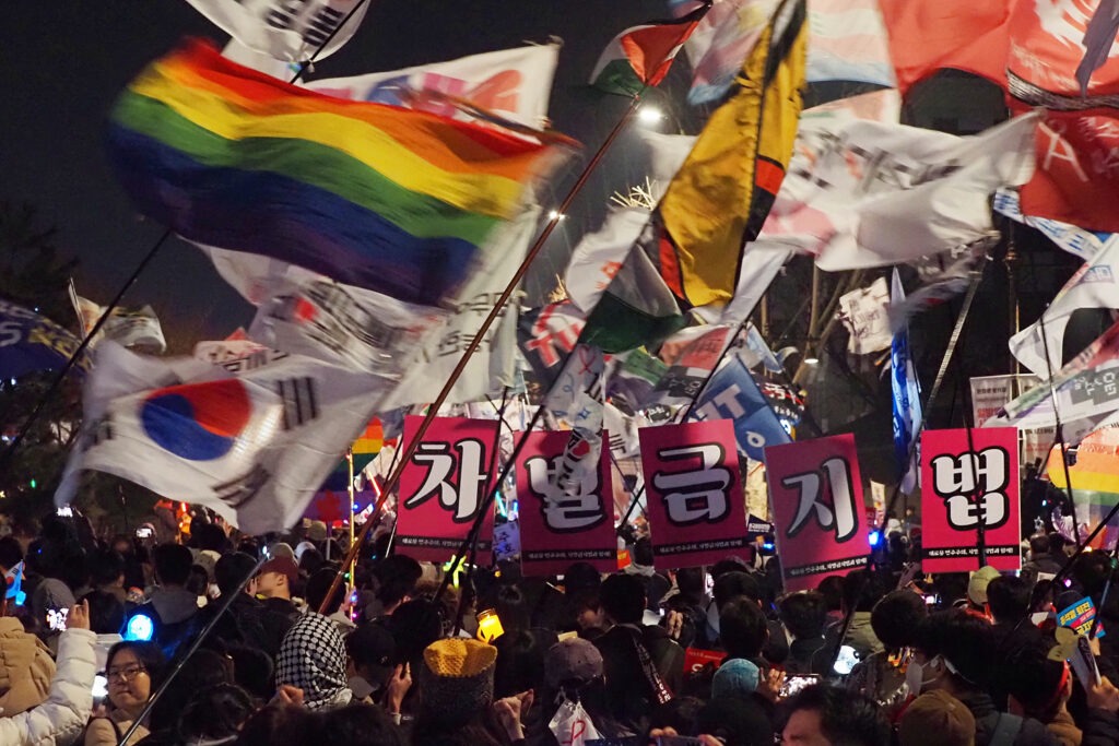 "차별금지법"이라고 적힌 대형 팻말, 시민들, 그리고 무지개 깃발을 비롯한 수많은 깃발들.