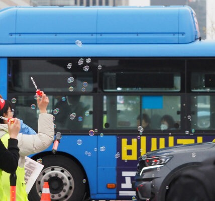 파란 시내버스가 지나는 앞으로 비상행동 스태프들이 고깔모자를 쓴 채 비눗방울을 불고 있다.